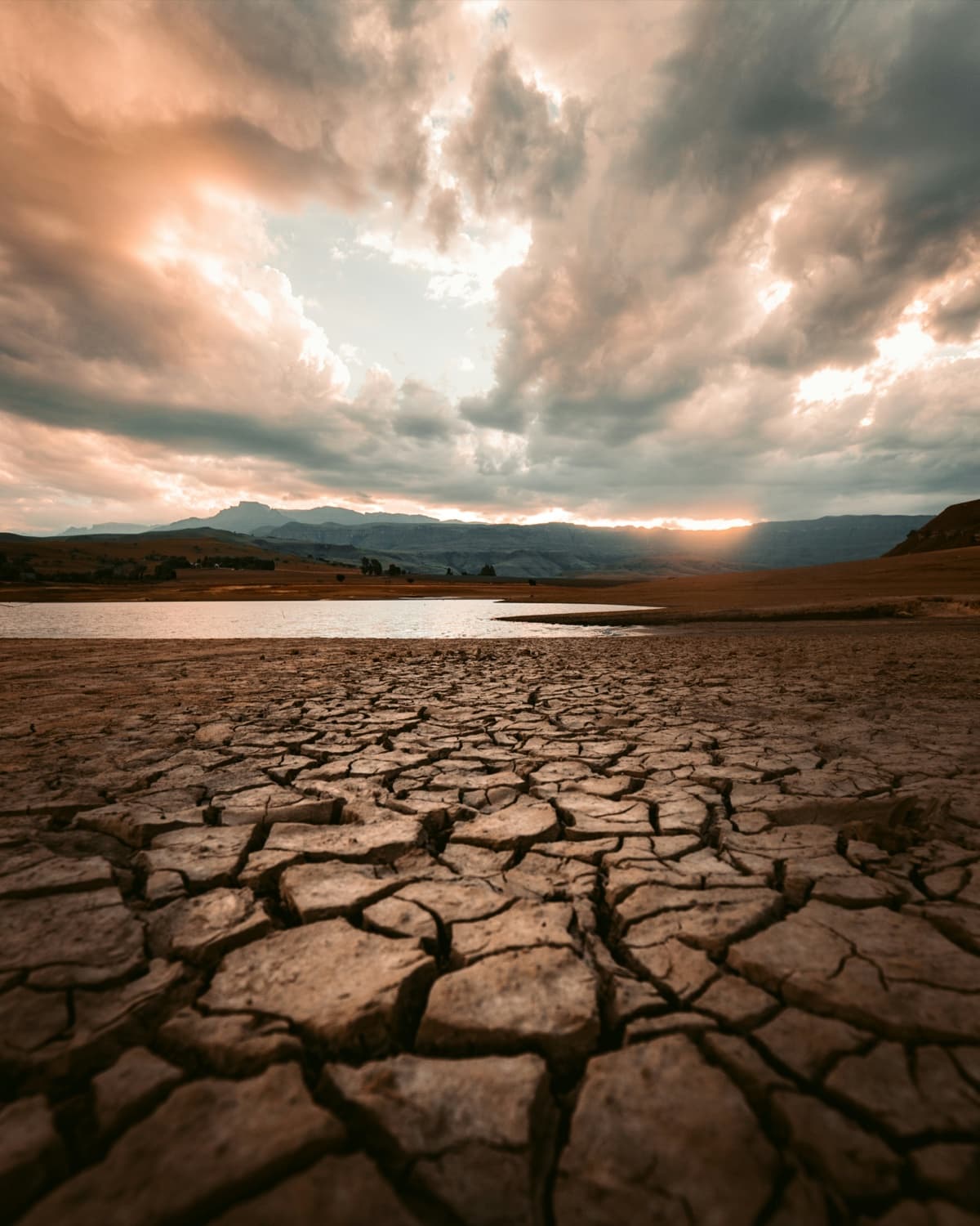 Cracked earth of a dried-out lake bed under a broken sky