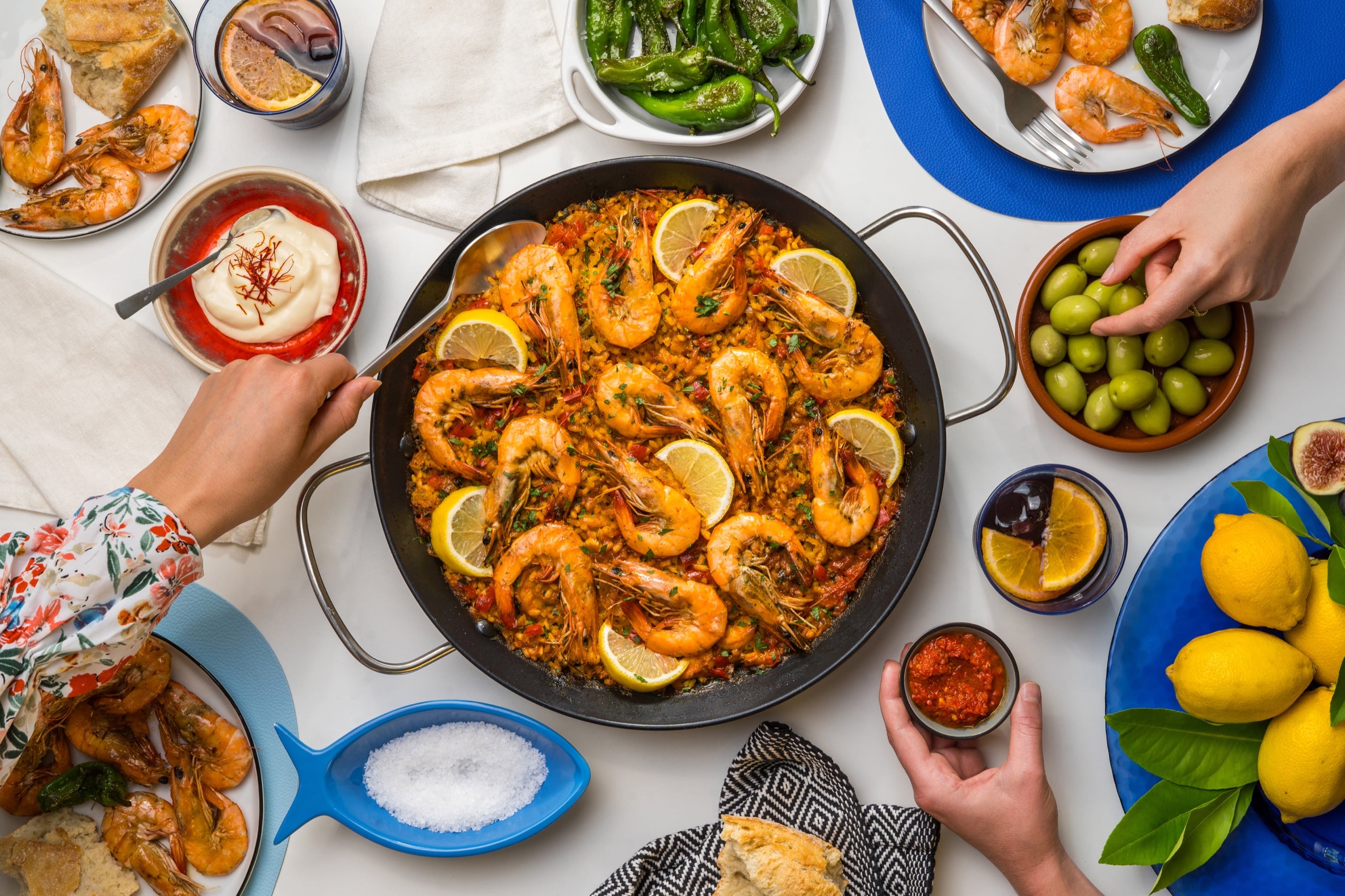 Paella with whole shrimp, lemon wedges and parsley in the pan