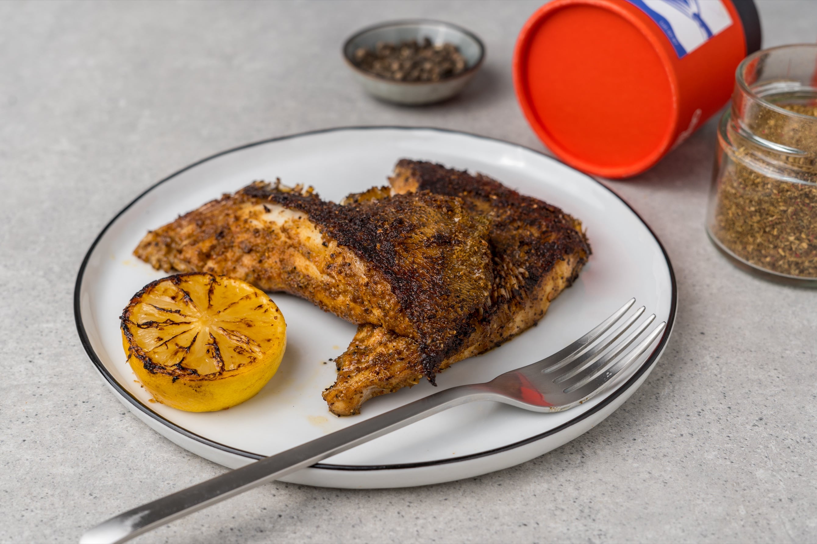Pan-seared grouper belly pieces in a spice rub with a charred lemon half