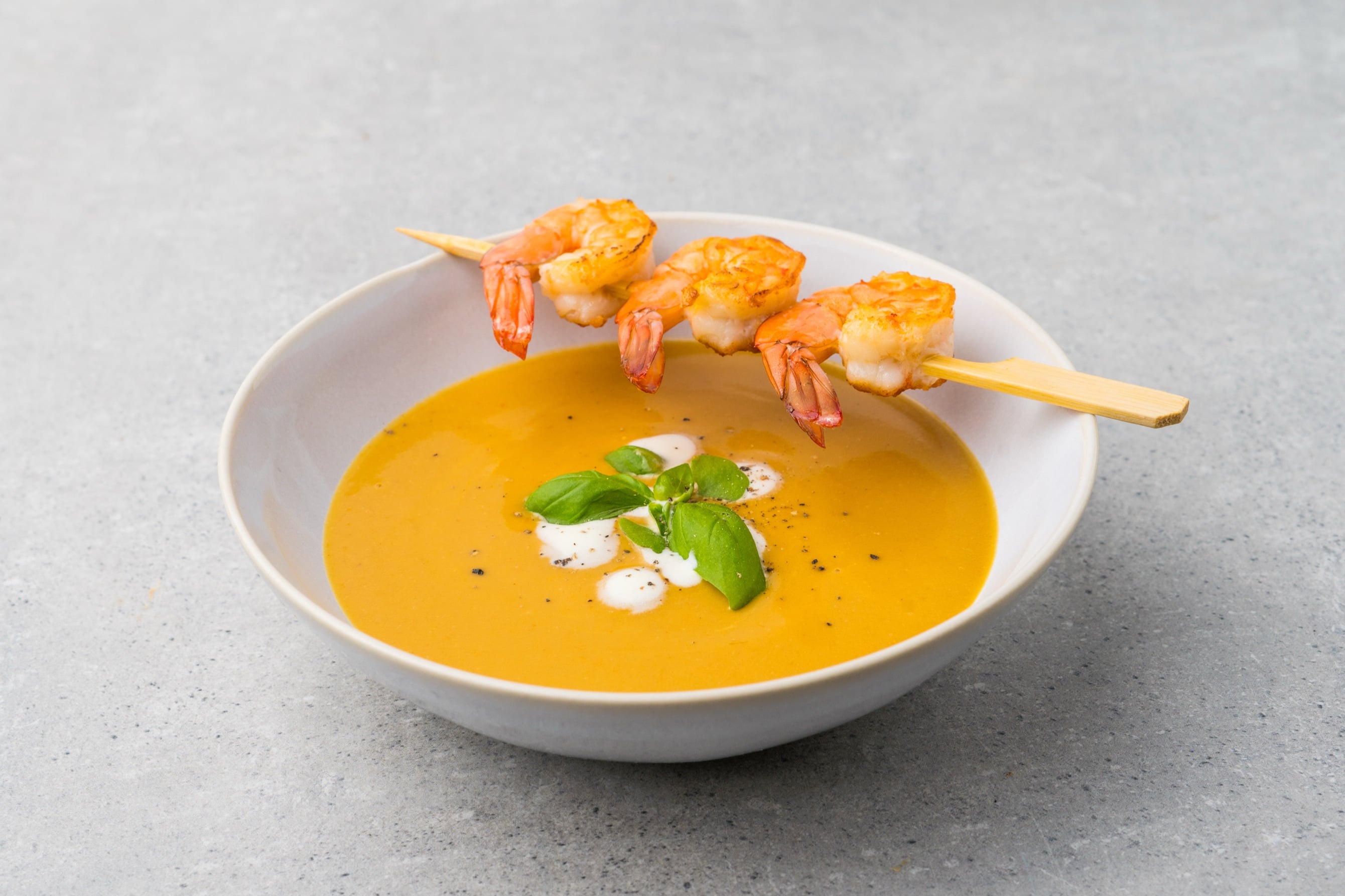 Bavarian shrimp cream soup with shrimp skewer, crème fraîche and basil